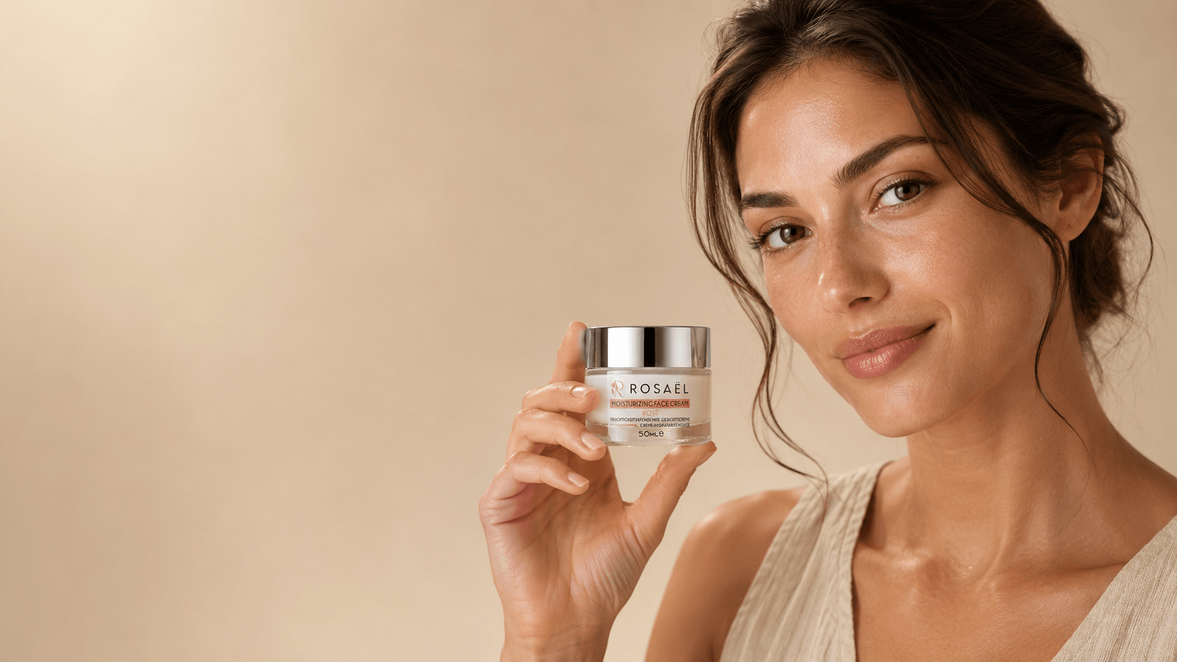 Natürliche Frau hält die Rosaël Moisturizing Face Cream im kleinen Glastiegel vor warmem beigem Studiohintergrund, links ruhiger Freiraum.