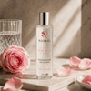Rosaël Rosenwasser in Glasflasche auf hellem Stein mit Rosenblüte und weichem Morgenlicht